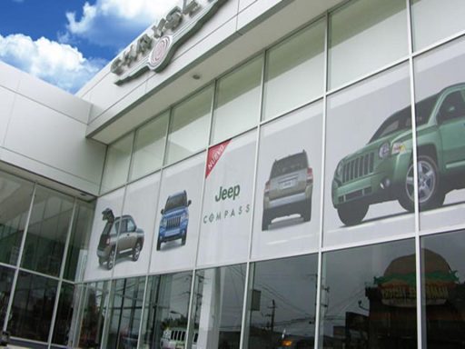 Fachada de concesionaria Jeep con vehículos en exhibición y cielo nublado al fondo.