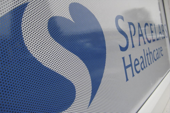 Logo de Spacelab Healthcare con un corazón azul sobre fondo claro.